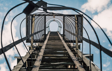 Naklejka premium old rusty staircase with damages against the blue sky and clouds