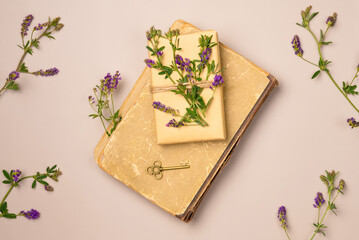 Antique book, gift, key and flowers on beige background from above. Vintage style. Flat lay, top view.