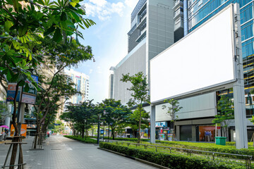 White blank billboard, banner on the streets of a modern city with lush green vegetation. Layout for advertising, design, signboard. Urban outdoor advertising