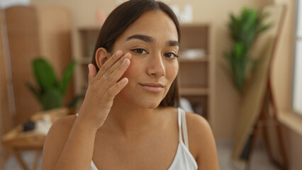 Woman applying skincare in spa wellness center with brunette hair and attractive features, creating a calm indoor beauty atmosphere.