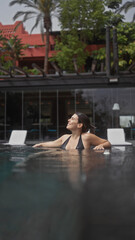 A relaxed young woman enjoys tranquility in a serene bali resort swimming pool, embodying holiday leisure.