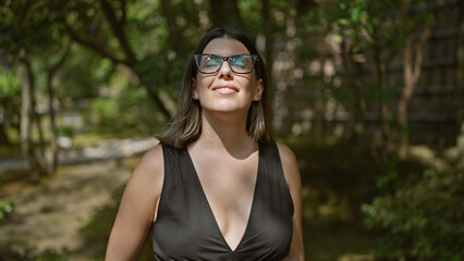 Fototapeta premium Beautiful young hispanic woman wearing glasses breathing with closed eyes enjoying sun at ginkaku-ji temple