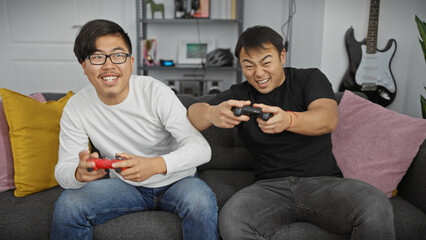 Two asian friends competing happily in a video game, sitting in a modern living room.