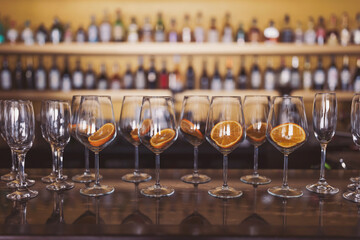 wine glasses on a brown bar table with slice of oranges are preparing to create an aperol spritz. process of preparation of a cocktail Aperol spritz. 