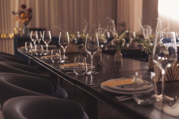 luxury tableware beautiful table setting in restaurant. banquette luxury arrangement plates and glasses. Glasses, forks, knives, napkins and decorative flower on a dark old brown wooden table.