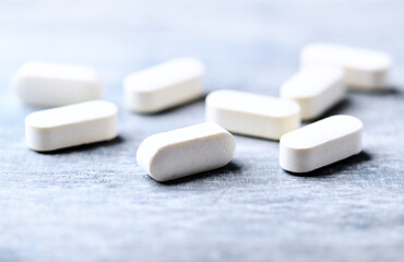 Amino acids tablets. Nutrition for bodybuilding. Fitness supplements on bright wooden background. Soft focus. Copy space.	