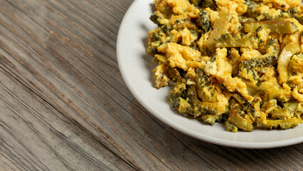 Homemade bitter melon stir-fry with eggs. Old wooden boards with space for text.