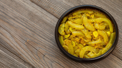Homemade zucchini curry with tomatillo, garlic, onion and spices. Old wooden board background with space for text.