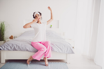 Photo of beautiful american funny yawning young girl in pajama wake up good morning routine bedroom indoors with big bed