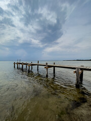 Rickety jetty jutting out from the beach under a threatening thunderstorm sky
