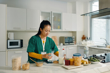 Woman in healthcare uniform preparing nutritious breakfast in modern kitchen with variety of ingredients and appliances around