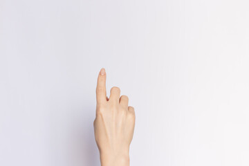 Female hand pointing upwards with index finger, close-up on  an empty white background.