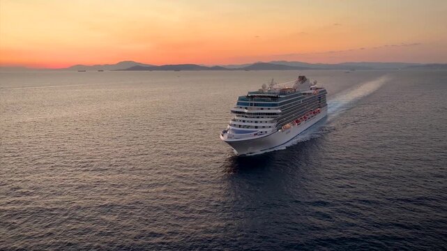 Aerial view of a generic cruise ship traveling over the ocean during golden summer sunset time