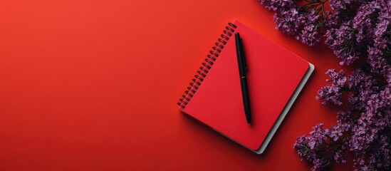 Spiral notebook and pen Notepad featuring a pen and flowers Lilac notebook on a red background. with copy space image. Place for adding text or design