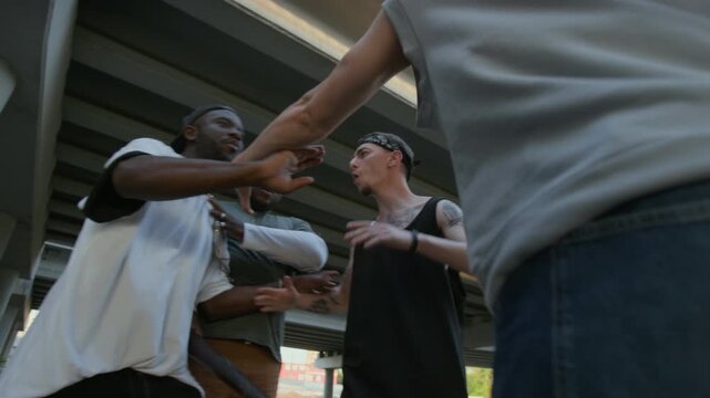 Aggressive criminals fighting with gun and baseball bat while having conflict on city street under urban bridge