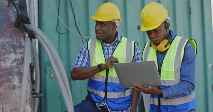 Factory engineers African American and construction crews are checking the factory equipment to make sure it is in good condition. Inspectors use technology to inspect via laptops. Concept Teamwork	

