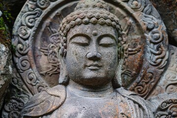Ancient stone buddha statue meditating peacefully with eyes closed, surrounded by intricate carvings