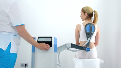 A physiotherapist administers advanced electromagnetic therapy for back pain relief using...