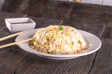rice with omelet and shrimp on a plate on a wooden background