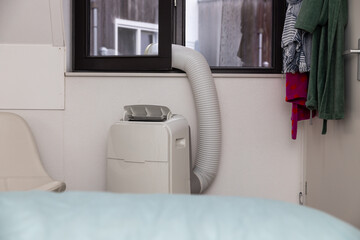 Mobile air conditioner removes warm air through open window in bedroom to prevent excessive temperature