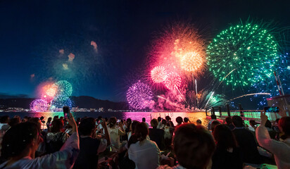 Lake Biwa Great Fireworks Festival. People are sitting on the lake shore watching beautiful summer fireworks. Shiga Prefecture, Japan.