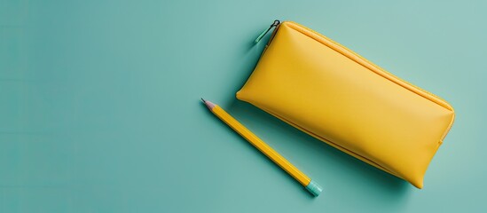 Back to school themed flat lay featuring a yellow pencil case against a mint background with a top view and copy space image