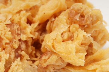Golden fried chicken with a crispy, flour-coated skin, photographed against a white background.