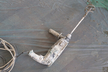 Large hammer drill with mixer bit attached and power cable top view. A blue plastic cleaning...