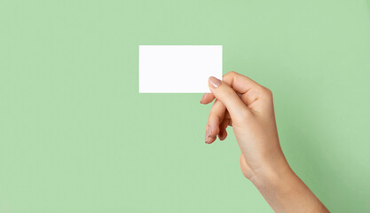 Female hands holds with cutaway, blank menu, discount card, business card on a green beauty...