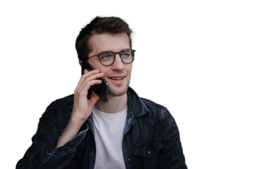 Young smiley brunette man in glasses, dark jeans shirt against transparent background talking by phone . Model speaking with agency manager about new shoot. Student calling to parents.
