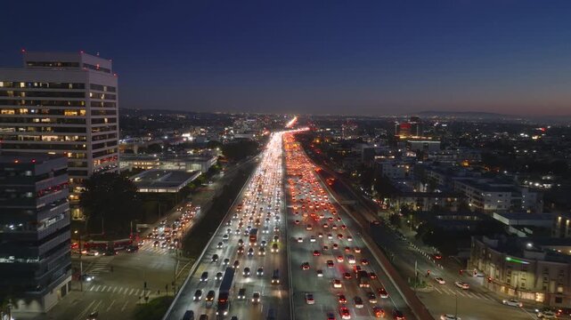 Observing from above, one can see the congested streets and highways of downtown Los Angeles at night, with the city lights shining brightly, illuminating the bustling urban landscape
