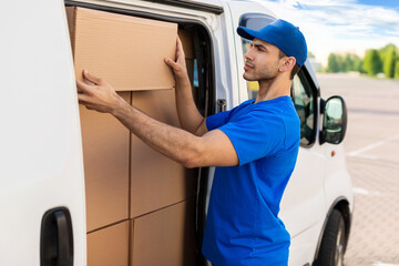 Man courier taking huge delivery box out from van, goods shipment and postal delivery shipping