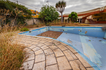 Abandoned swimming pool and vandalized abandoned hotel. Graffiti on the pool. Abandoned garden. Tenerife, Bajamar, Canary Islands.