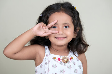  A delightful little girl with sparkling eyes, breaking into a wide, infectious smile. Her expression radiates pure happiness and innocence.