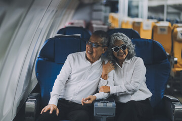 Happy elderly senior couple of travelers with suitcase in airport