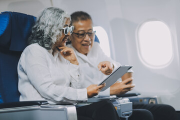 Happy elderly senior couple of travelers with suitcase in airport