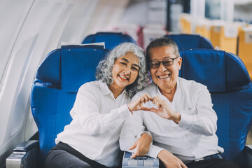 .A mature couple enjoys a plane ride sitting near the window. They looked out into the sky. Immerse yourself in the scenery and excitement of the journey. To create precious memories together