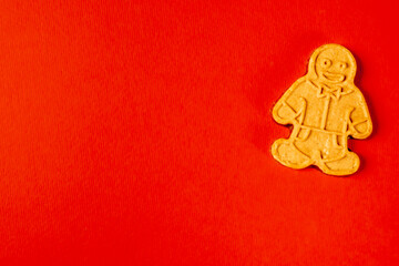 Gingerbread man cookie, in a playful design, placed on a vibrant red background. Concept of holiday treats and festive cheer. Copy space