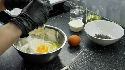 Breaking the egg into the flour. The process of making muffins.