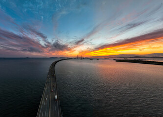 Songdo-dong, Yeonsu-gu, Incheon, South Korea - July 14, 2022: Aerial and sunset view of cars driving on the road of Incheon Bridge againt glow in the sky