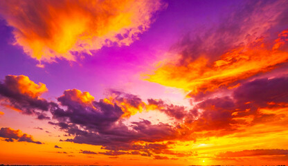 Obraz premium A stunning sky ablaze with vivid hues of orange, purple, and yellow, capturing the dramatic beauty of a sunset as the colors streak across the horizon.