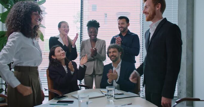 Ending of meeting. Man and woman standing in front of each other and shaking hands. Group of managers behind them clapping their hands. Positive feedback. Closing important deal. Business concept.