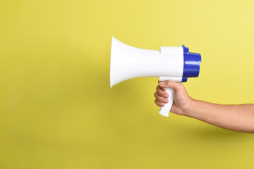 Megaphone in man's hand isolated on yellow background. Concept of hiring, advertising something. Banner. Copy space