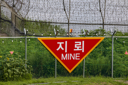 Paju-si, Gyeonggi-do, South Korea - August 4, 2022: A mine warning sign on red inverted triangle plate are attached on barbed wire at Imjingak of Pyeonghwa Nuri
