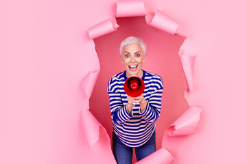 Photo of glad cheerful senior woman wear striped stylish clothes break paper wall announce news...