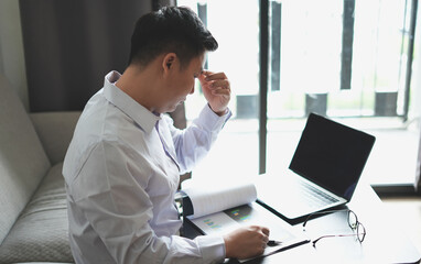 Young asian business man massaging rubbing stiff sore neck and headache tensed muscles fatigued...