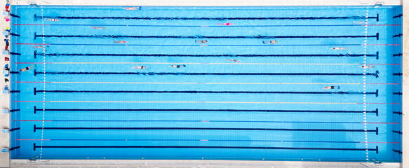 Drone video of swimmers in a clear blue pool, captured from above. The top-down view emphasizes the...