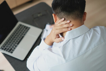 Young asian business man massaging rubbing stiff sore neck and headache tensed muscles fatigued...