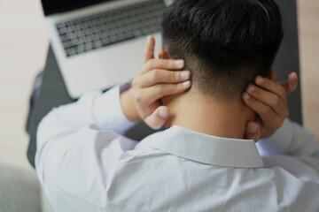 Young asian business man massaging rubbing stiff sore neck and headache tensed muscles fatigued from computer work in incorrect posture feeling hurt joint shoulder back pain, office syndrome concept.