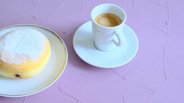 Close-up of berliner cake on a white plate and a cup of espresso	